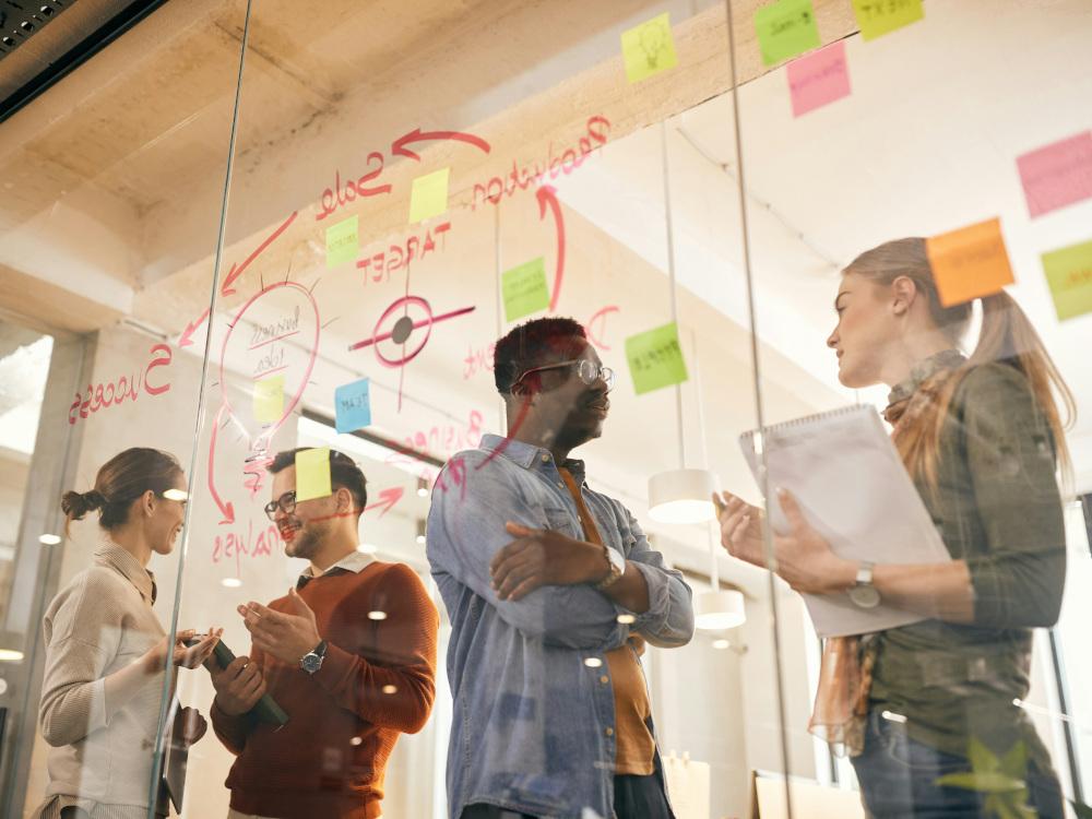 Menschen im Gespräch hinter einer Glaswand mit Post-its