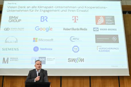 Referent Scharpf dankte den Unternehmen, hier als Logos im Hintergrund