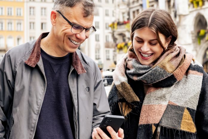 Mann und Frau auf dem Marienplatz im Gespräch und mit einem Handy