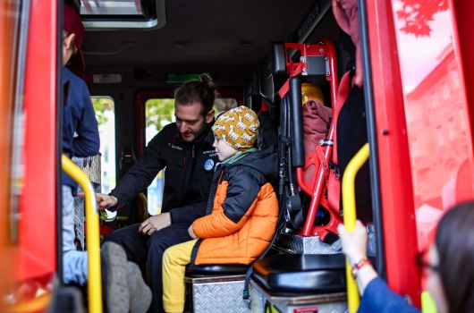Zwei Jungen und ein Erwachsener in einem Feuerwehrfahrzeug