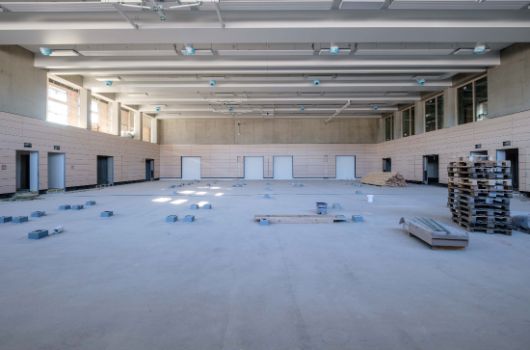Blick in die Sporthalle. Die Prallwand sowie die Deckenarbeiten inkl. der Leuchten sind fertig gestellt.