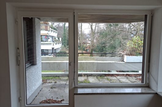 Harthauser25c - Blick auf überdachten Balkonbereich und Grünflächen vom Wohnzimmer aus