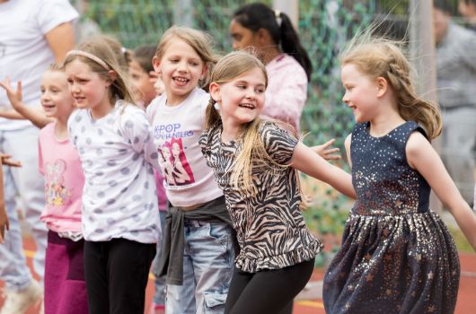 Kinder tanzen auf dem Schulsportplatz