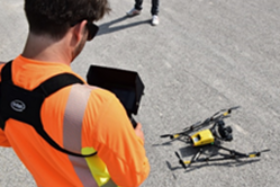 Mitarbeiter in Warnweste steuert Drohne