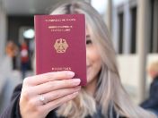Eine Person mit langen Haaren hält einen Reisepass.