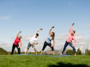 Bild: Vier lächelnde Sportler*innen beim Yoga im Olympiapark