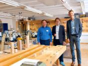 Bildungsreferent Herr Kraus, der Schulleiter und eine Lehrkraft posieren zusammen in der Holzwerkstatt der Schule für ein Foto. 