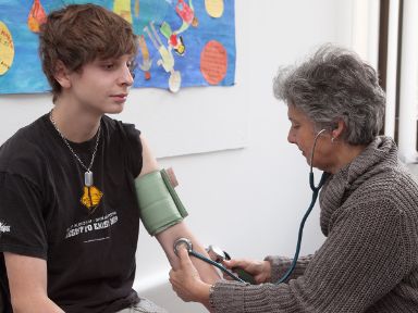 Ärztin misst Blutdruck eines jungen Mannes