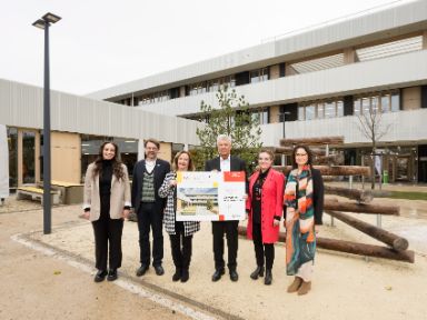 Auf dem Bild sind Oberbürgermeister Dieter Reiter, Stadtschulrat Florian Kraus, Baureferentin Dr.-Ing. Jeanne-Marie Ehbauer, Bettina Betz, Vera Reindl und Lily Kroiß vor der Grundschule zu sehen.