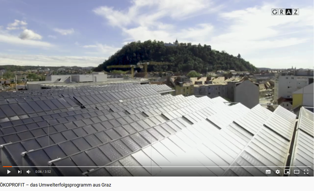 Screenshot aus dem ÖKOPROFIT-Video des Umweltamtes Graz: Blick über eine Photovoltaikanlage und die Stadt Graz