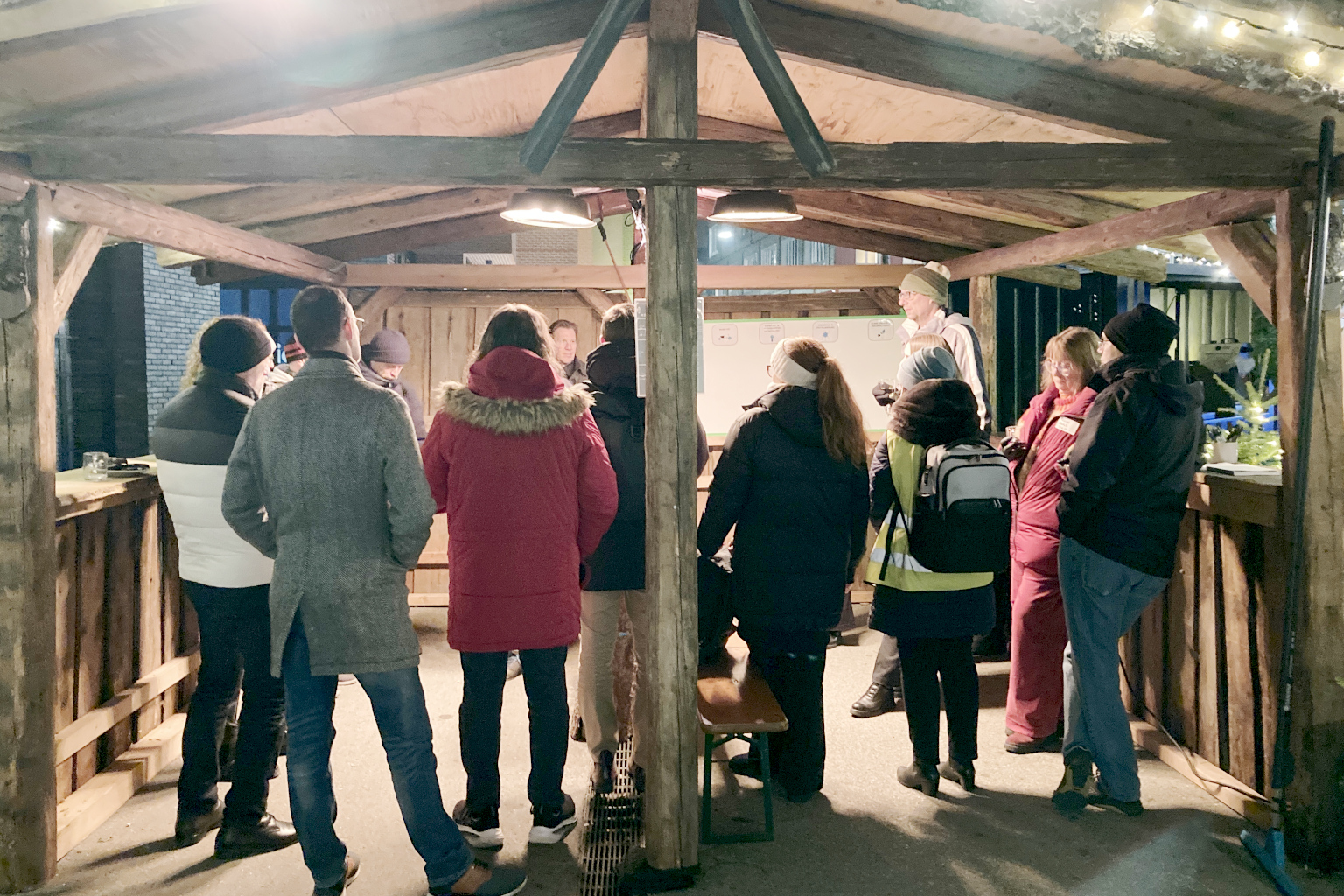 Mitarbeitende aus dem Gewerbegebiet stehen zusammen in kleiner Adventshütte