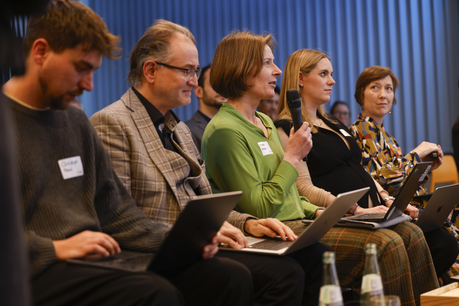 Personen sitzen in einer Reihe, eine Person spricht