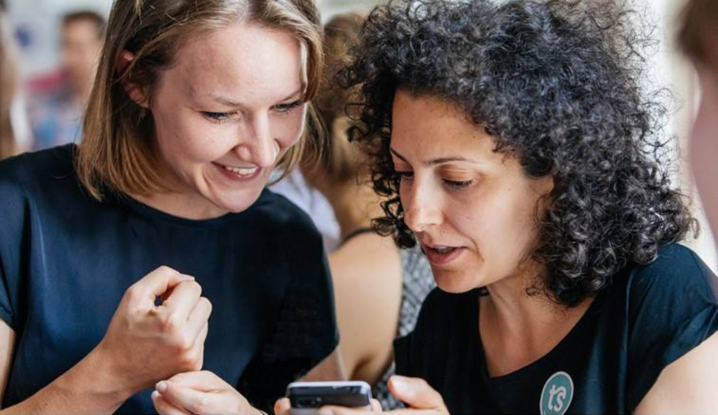 Zwei Frauen verfolgen das Voting für den Wettbewerb am Handy